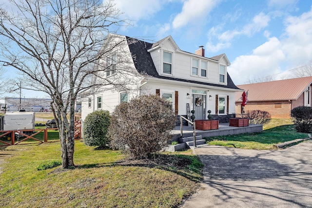 view of front of house with a shingled roof, a chimney, a front yard, and fence