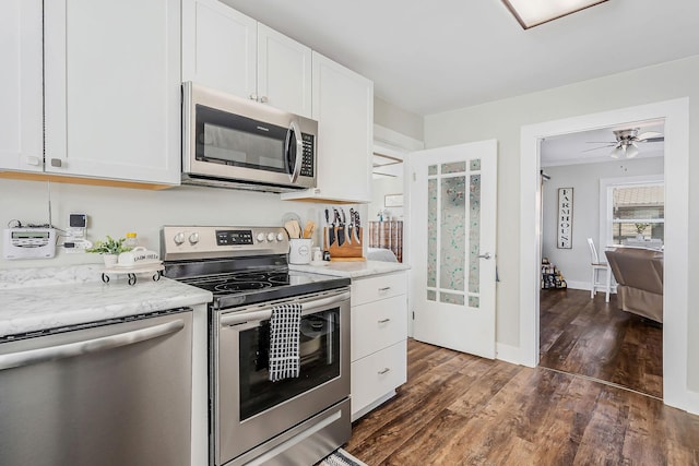 kitchen featuring stainless steel appliances, dark wood-type flooring, baseboards, white cabinets, and ornamental molding