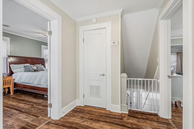 hall with baseboards, visible vents, wood finished floors, crown molding, and a healthy amount of sunlight