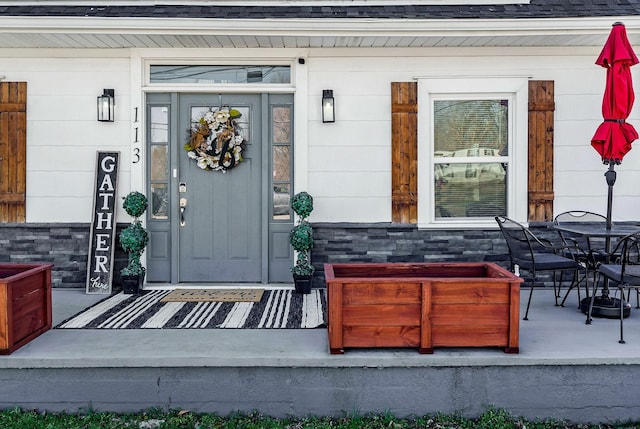 property entrance with a shingled roof and outdoor dining space