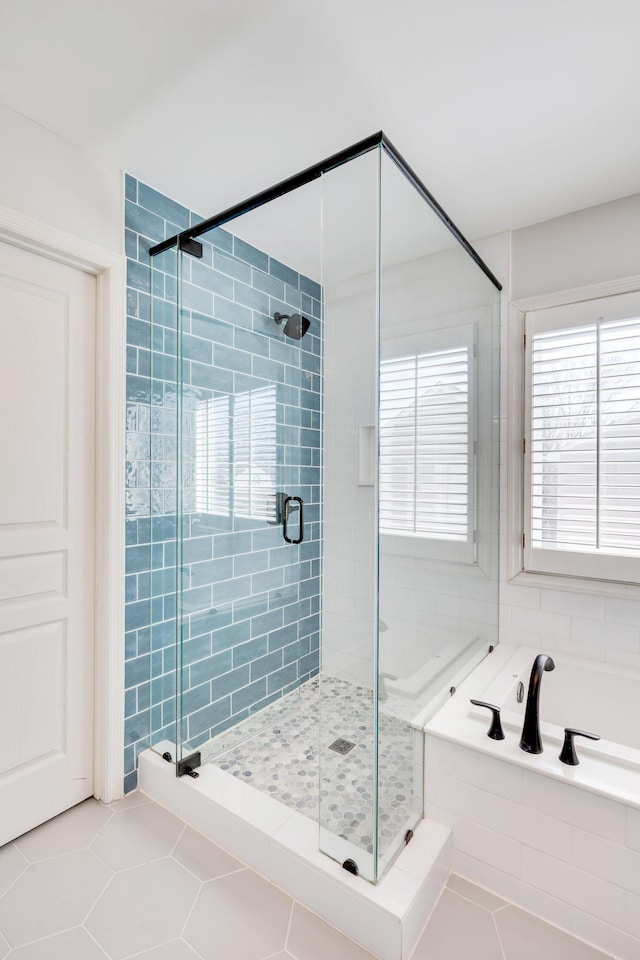 bathroom with a stall shower, tile patterned flooring, and a garden tub