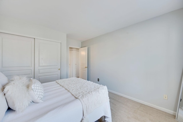 bedroom with a closet, light carpet, and baseboards