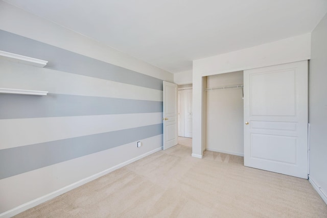 unfurnished bedroom featuring baseboards, a closet, and light colored carpet