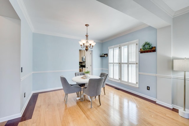 dining room featuring baseboards, light wood finished floors, a chandelier, and crown molding