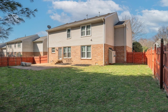 rear view of property featuring brick siding, a lawn, a fenced backyard, and a patio