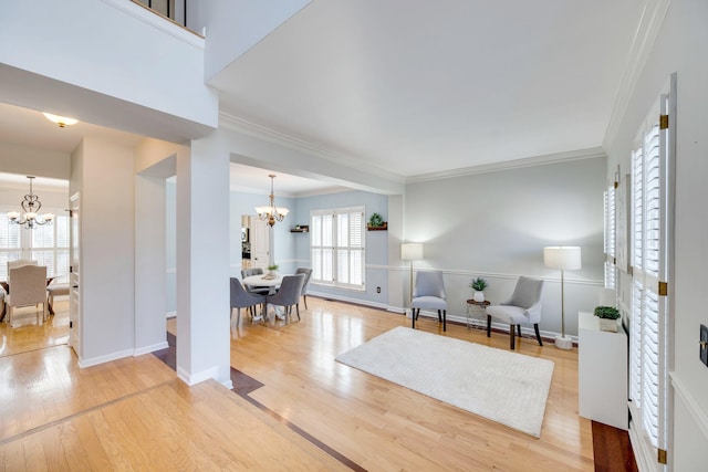 living area with a chandelier, crown molding, baseboards, and wood finished floors