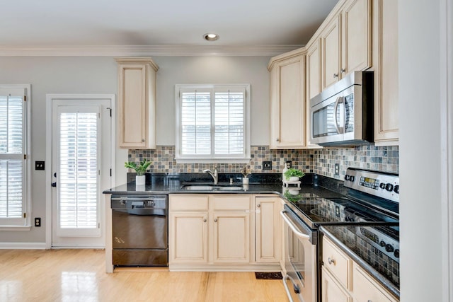 kitchen with ornamental molding, appliances with stainless steel finishes, cream cabinets, and a sink