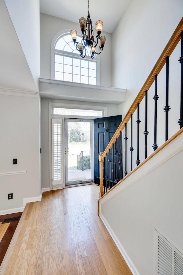 foyer entrance featuring visible vents, plenty of natural light, stairway, and a high ceiling