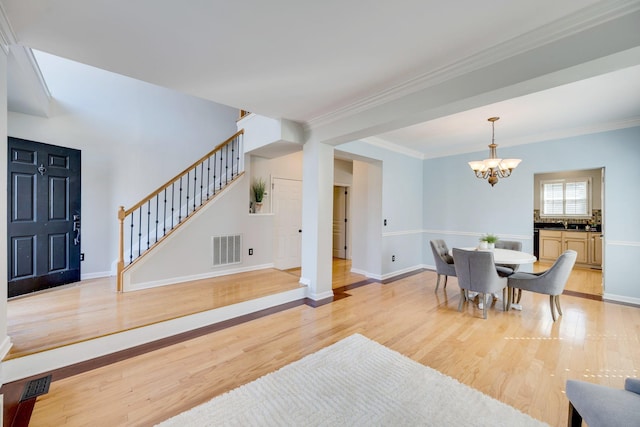 dining space with visible vents, baseboards, stairs, light wood-style floors, and an inviting chandelier