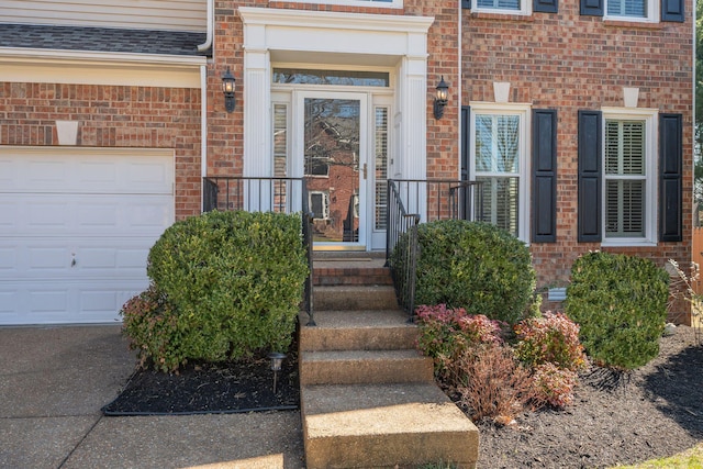 view of exterior entry with brick siding and an attached garage