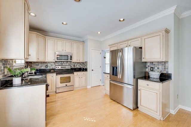 kitchen featuring appliances with stainless steel finishes, light wood-type flooring, ornamental molding, and cream cabinets