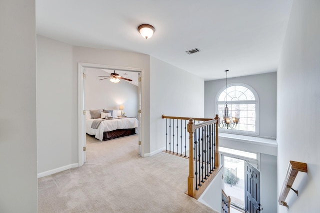 corridor with carpet, visible vents, an inviting chandelier, an upstairs landing, and baseboards