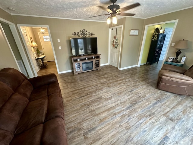 living room featuring baseboards, a ceiling fan, ornamental molding, wood finished floors, and a textured ceiling