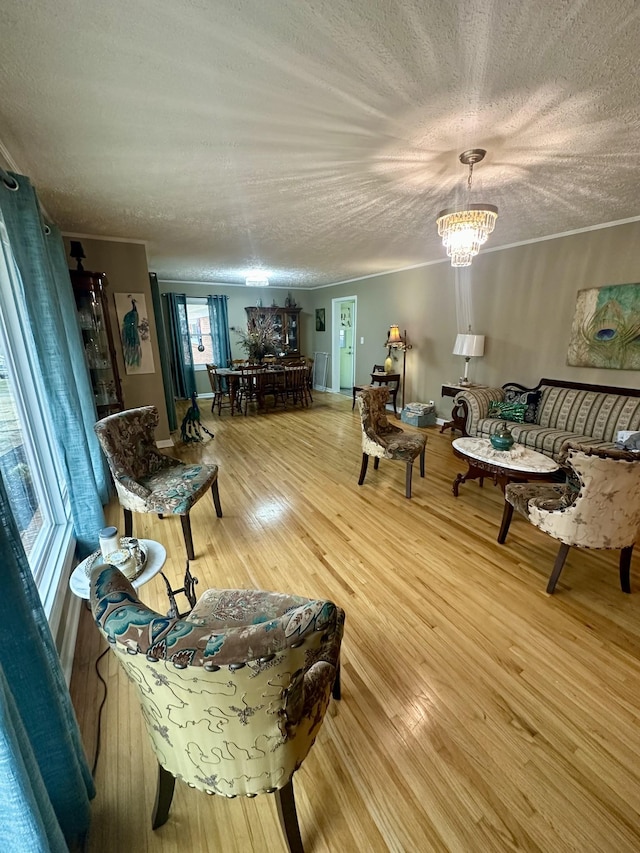 living room with light wood-type flooring, an inviting chandelier, and a textured ceiling