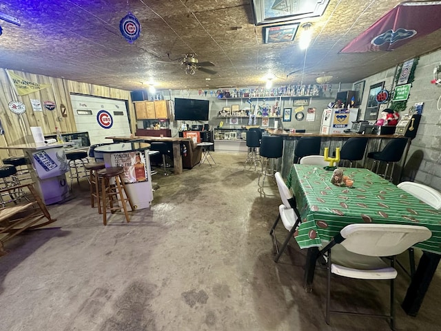 miscellaneous room featuring concrete block wall, a garage, a bar, and unfinished concrete flooring