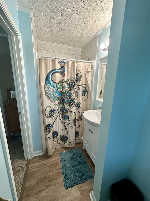 full bath featuring ornamental molding, a textured ceiling, vanity, and wood finished floors