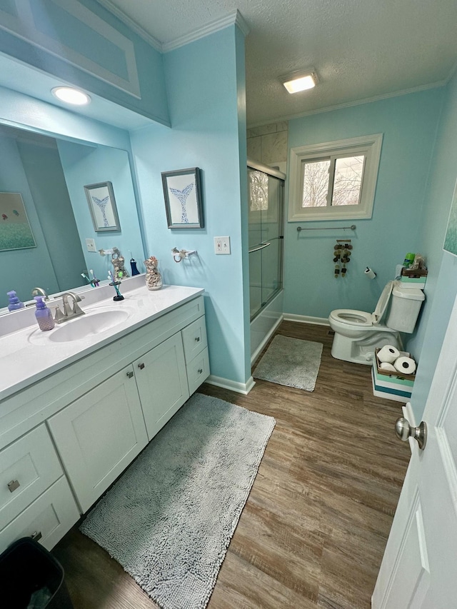 bathroom featuring toilet, enclosed tub / shower combo, wood finished floors, a textured ceiling, and vanity