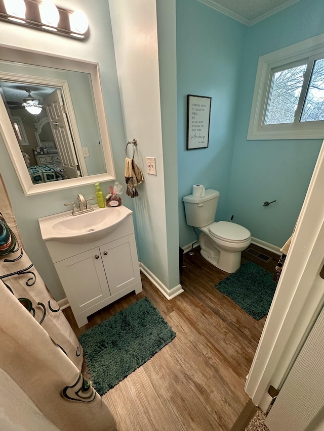 bathroom featuring visible vents, toilet, vanity, wood finished floors, and baseboards