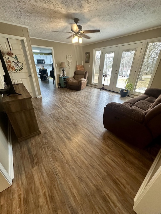 living area featuring french doors, crown molding, a textured ceiling, and wood finished floors