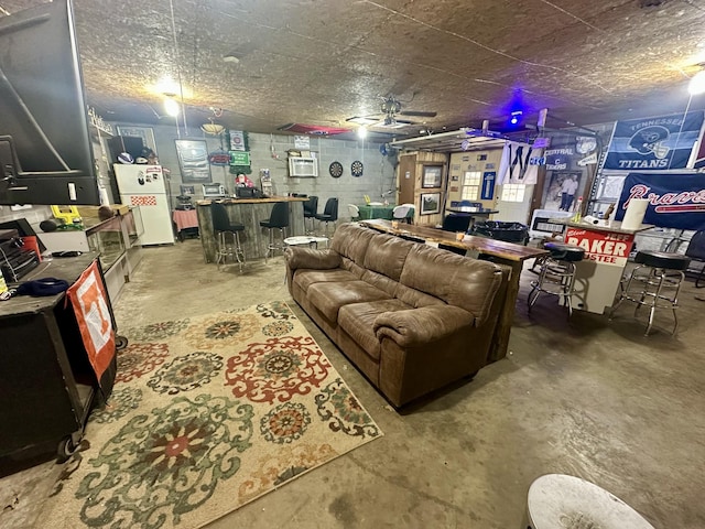 interior space with concrete flooring, a bar, and concrete block wall