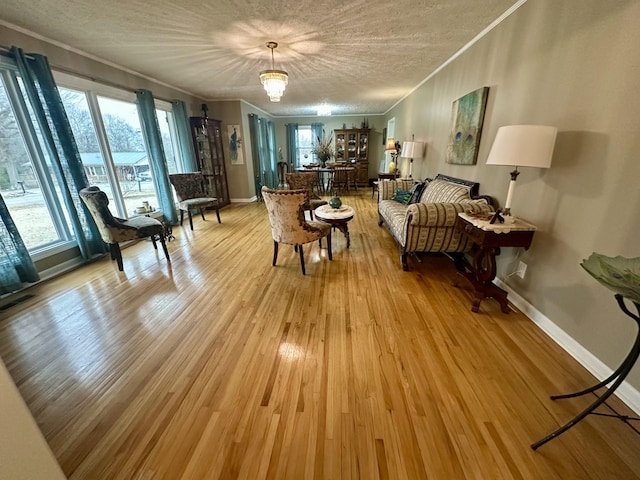 sitting room with baseboards, crown molding, light wood-style flooring, and a textured ceiling