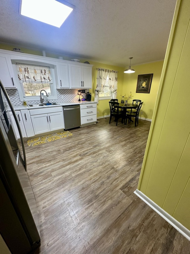 kitchen featuring a sink, white cabinets, light wood-type flooring, dishwasher, and tasteful backsplash