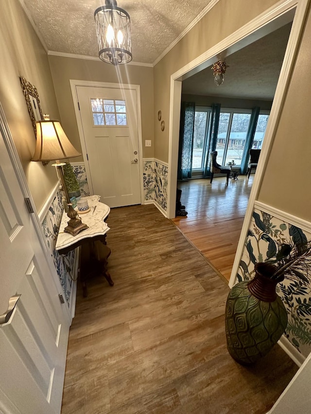 foyer featuring crown molding, a textured ceiling, an inviting chandelier, and wood finished floors