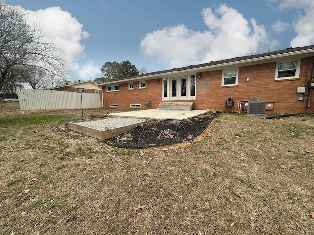 rear view of property with brick siding, fence, central AC, and french doors