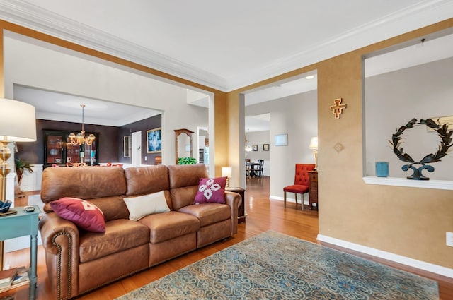 living area featuring a chandelier, ornamental molding, wood finished floors, and baseboards