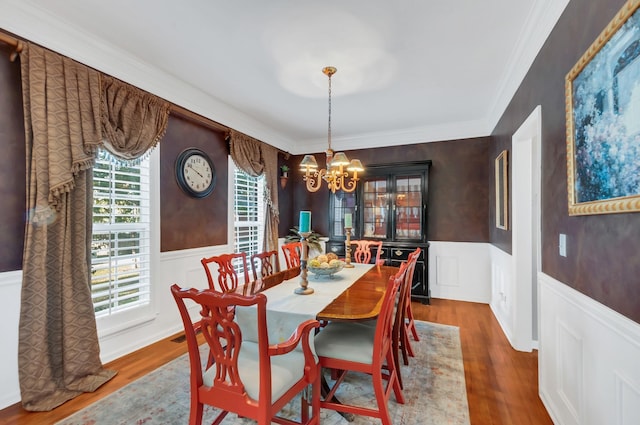 dining room with a wainscoted wall, wood finished floors, and a chandelier