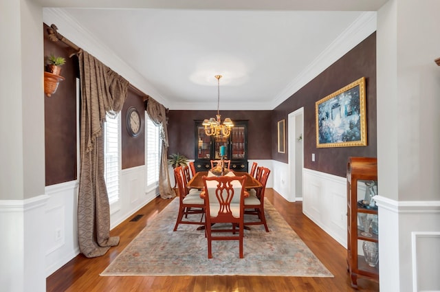 dining room with a chandelier, a wainscoted wall, visible vents, and wood finished floors