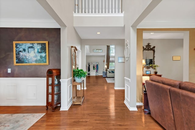 entryway with ornamental molding, wainscoting, baseboards, and wood finished floors