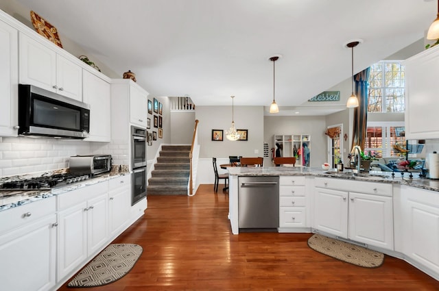 kitchen with stainless steel appliances, decorative backsplash, dark wood-type flooring, white cabinetry, and a sink