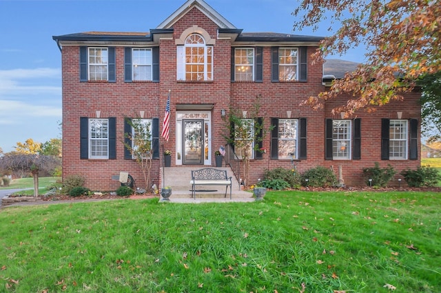 colonial inspired home with a front yard and brick siding