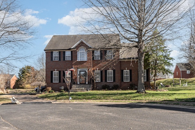 colonial house featuring brick siding and a front lawn