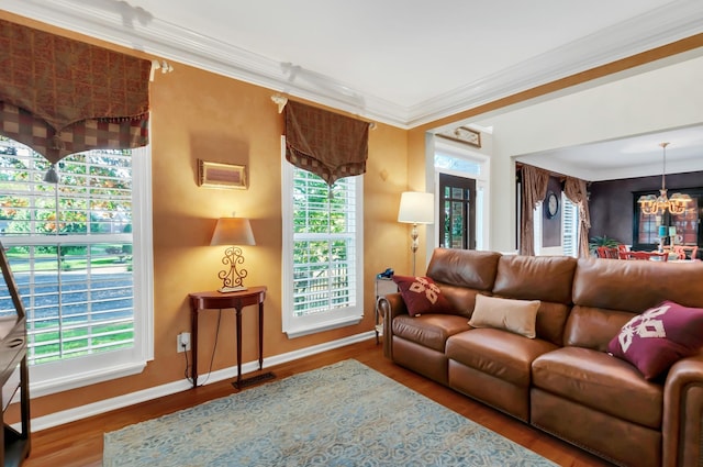 living room featuring an inviting chandelier, baseboards, crown molding, and wood finished floors