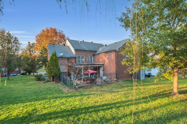 back of house featuring a lawn and brick siding