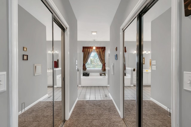 hall featuring carpet, tile patterned flooring, and baseboards