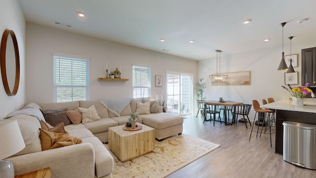 living room featuring light wood-style flooring, visible vents, a notable chandelier, and recessed lighting