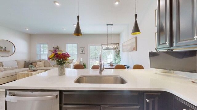 kitchen with recessed lighting, light countertops, open floor plan, a sink, and dishwasher