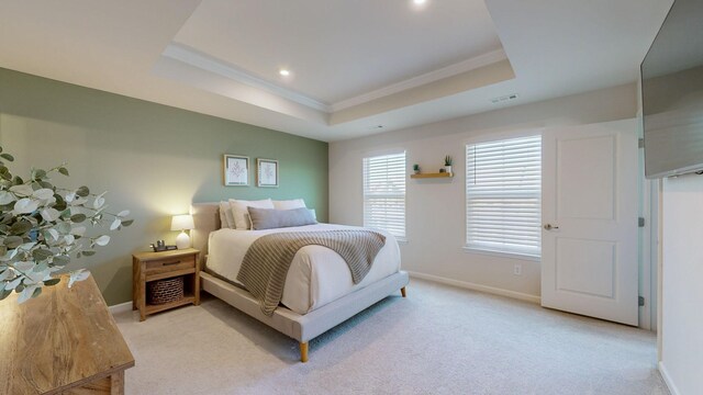 bedroom featuring a tray ceiling, visible vents, light carpet, and baseboards