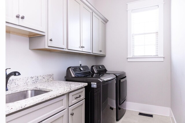 laundry area with cabinet space, baseboards, a sink, and independent washer and dryer