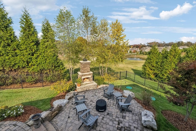 view of patio with an outdoor stone fireplace, a fenced backyard, and a water view