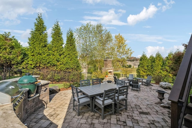 view of patio / terrace with fence, an outdoor stone fireplace, outdoor dining area, and exterior kitchen