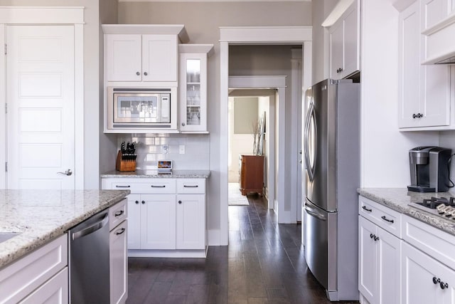 kitchen with dark wood-style floors, stainless steel appliances, wall chimney range hood, and white cabinets