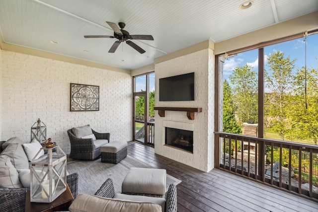 living area with brick wall, wood-type flooring, a large fireplace, and ceiling fan