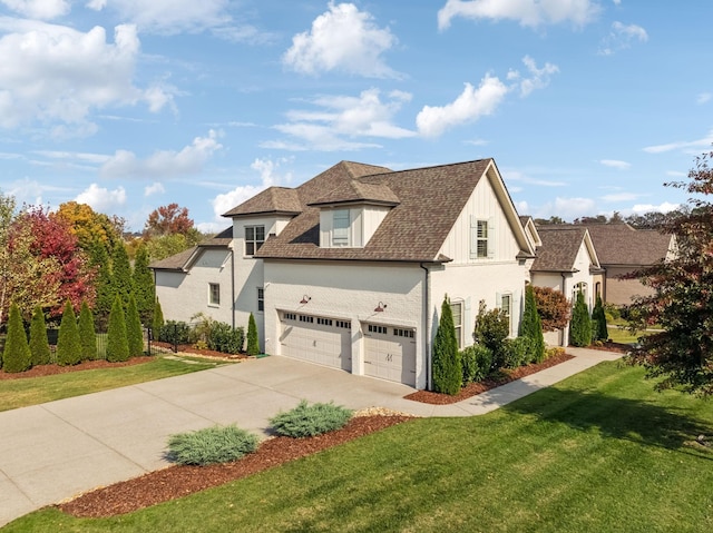 view of front of property featuring a garage, a front yard, roof with shingles, and driveway