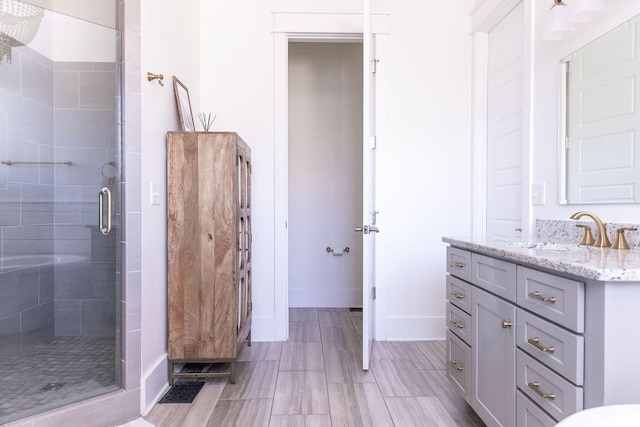 bathroom with a shower stall, vanity, and baseboards