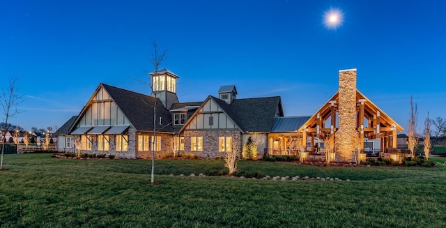 back of house featuring metal roof, a lawn, a chimney, and a standing seam roof