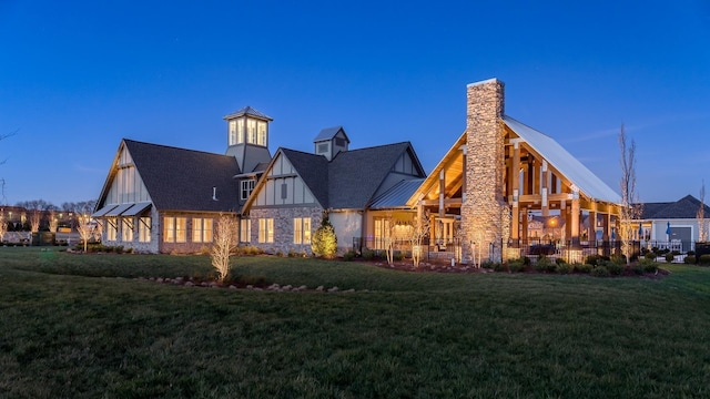 rear view of property featuring stone siding, a yard, and a chimney